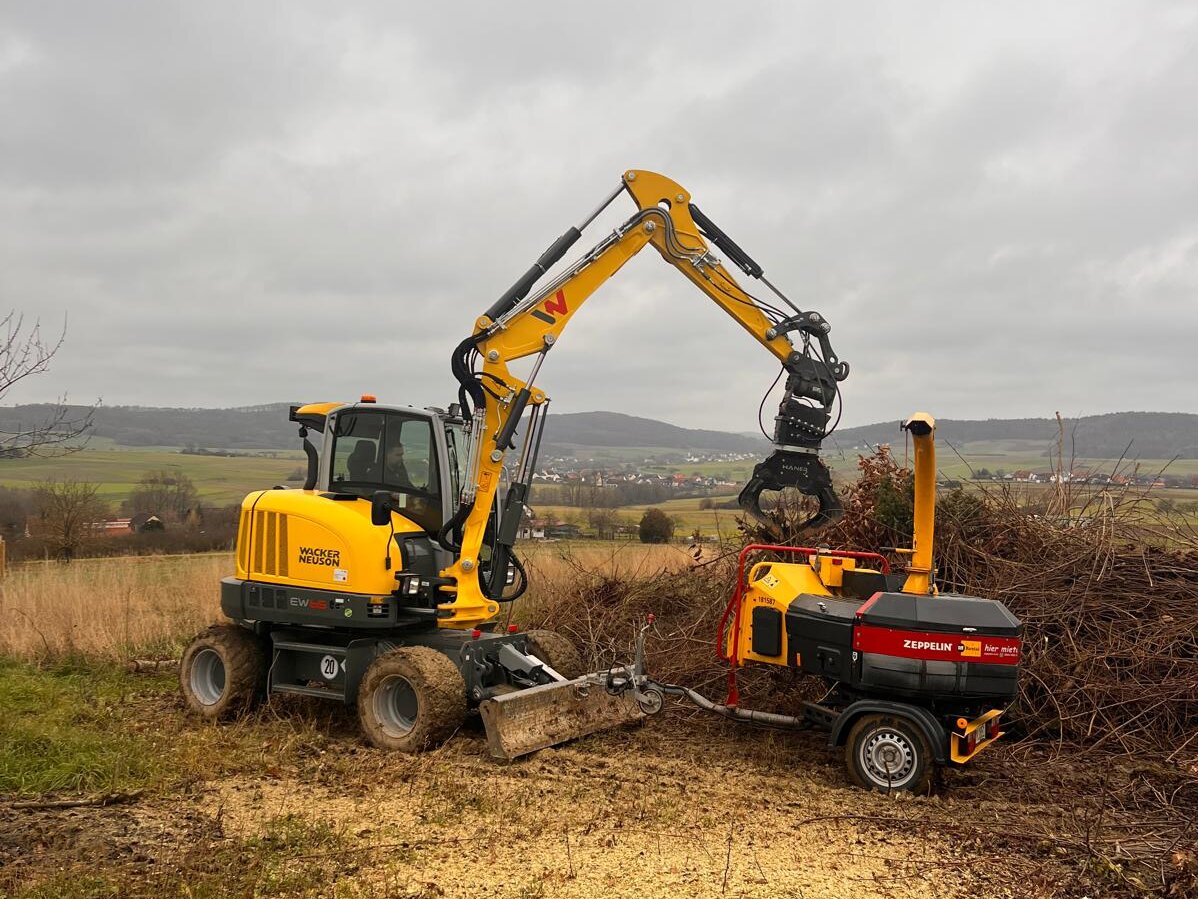 Mobilbagger mit Haecksler beim Gruenschnitt
