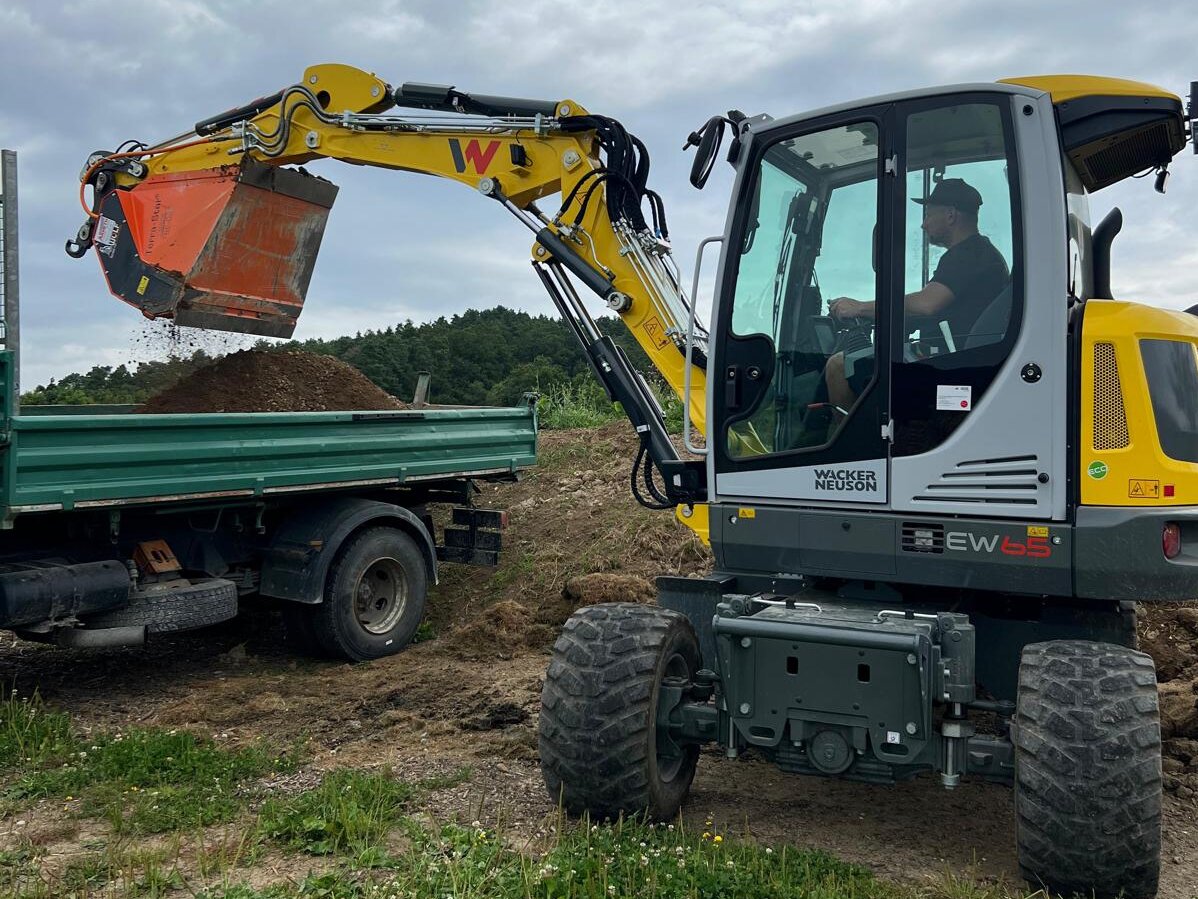 Mobilbagger beim Erdaushub und Beladung eines LKW