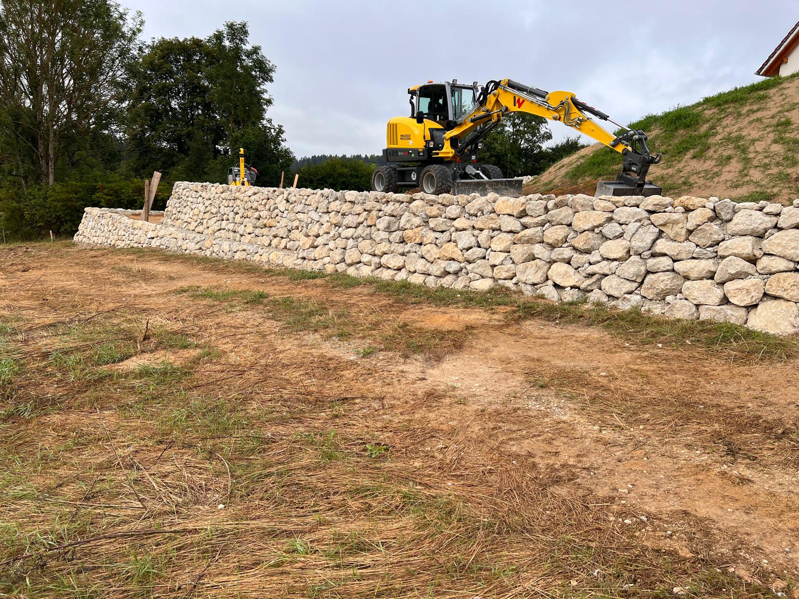 Bagger beim Bau einer Natursteinmauer zur Hangsicherung